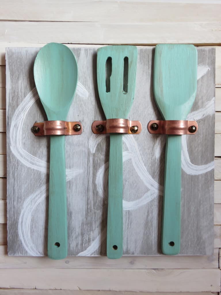 Average But Inspired shows you how to make unique art for your kitchen using copper pipe straps, wooden utensils and some paint!