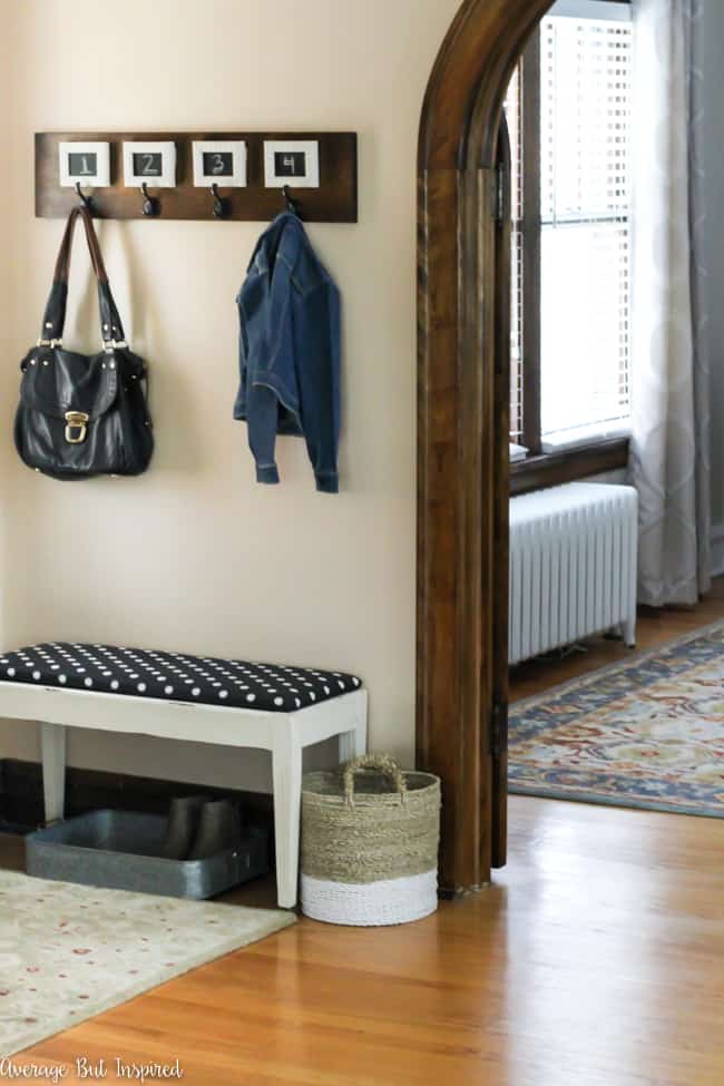 Love this small foyer decor! A pretty table, potted plant, and decorative accessories make it a functional and stylish space. The bench and wall hooks add to the functionality of this small entryway!