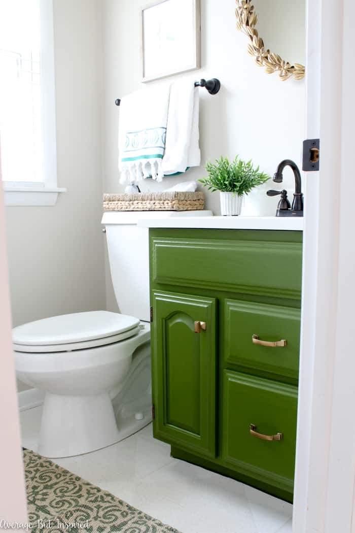 A painted olive green bathroom vanity adds a bold touch to a small powder room. See how this 1990s powder room was transformed in a day!