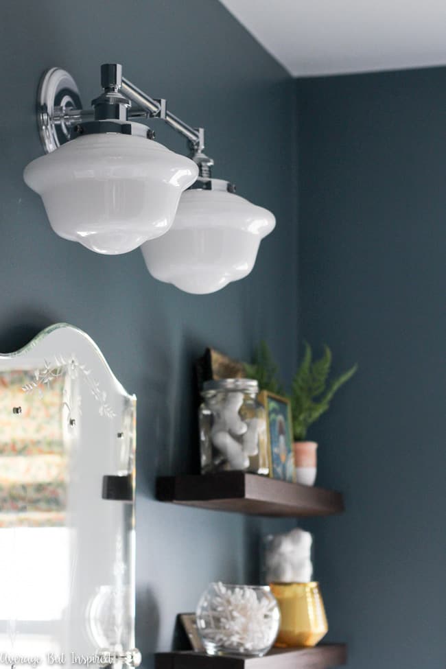 This vintage look milk glass schoolhouse bathroom sconce paired with moody blue paint (Charlotte Slate by Benjamin Moore) make a beautiful statement in a small bathroom.