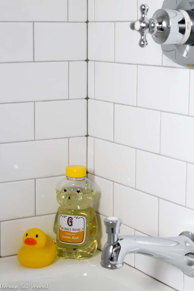 Vintage inspired bath fixtures help make this white subway tile shower surround feel true to the 1920s period of the home.