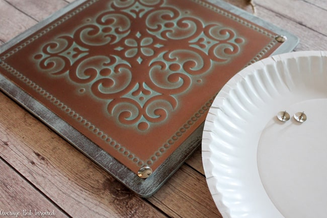 Adding push pins to the vintage tin tile wall art gives it the look of nails.