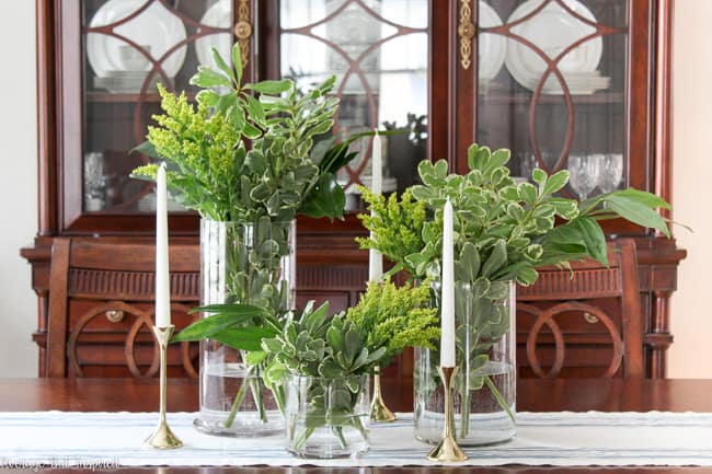 With around $10 of grocery store greenery, you can create a gorgeous centerpiece for your home or any event! Using different shades of foliage and a special trick, you'll make a greenery centerpiece that is beautiful and budget-friendly.