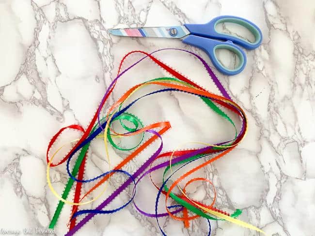To make a DIY rainbow sculpture, cut lengths of rainbow ribbon.
