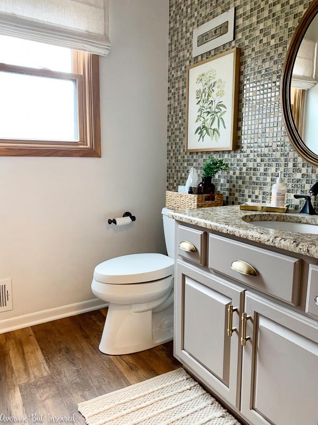 In the first phase of this powder room makeover, this blogger painted her vanity, painted her baseboards, and added new hardware to the vanity.