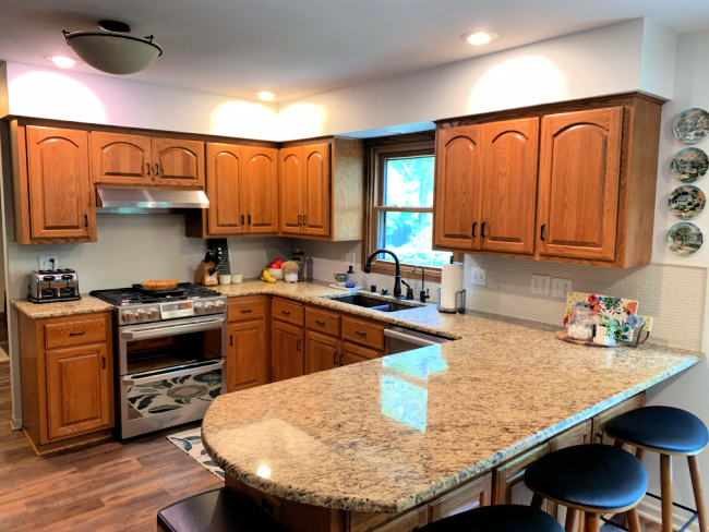 This is the BEFORE photo of a kitchen with oak cabinets and a kitchen soffit. The homeowner did a creative soffit makeover to help disguise it, and is painting the cabinets.