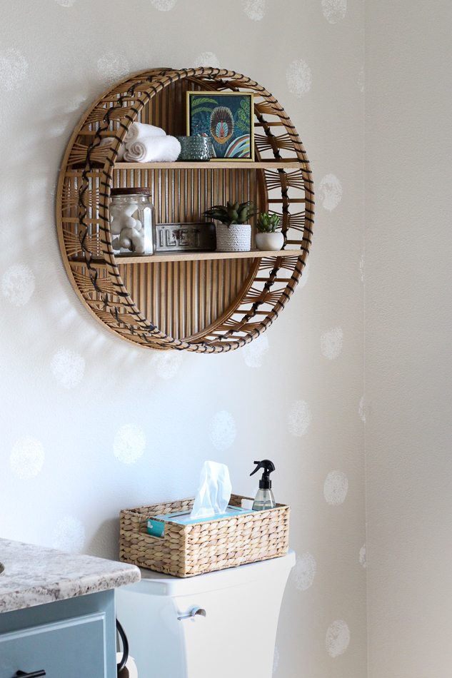 A rattan round shelf over the toilet is a fun place for storing cute bathroom accessories. The round shelf plays up the polka dot accent wall on which it hangs.