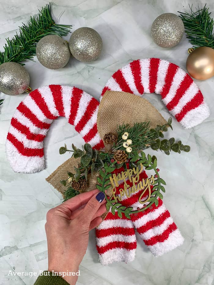 Add embellishments like faux greenery and a Christmas ornament to make this candy cane wreath special.