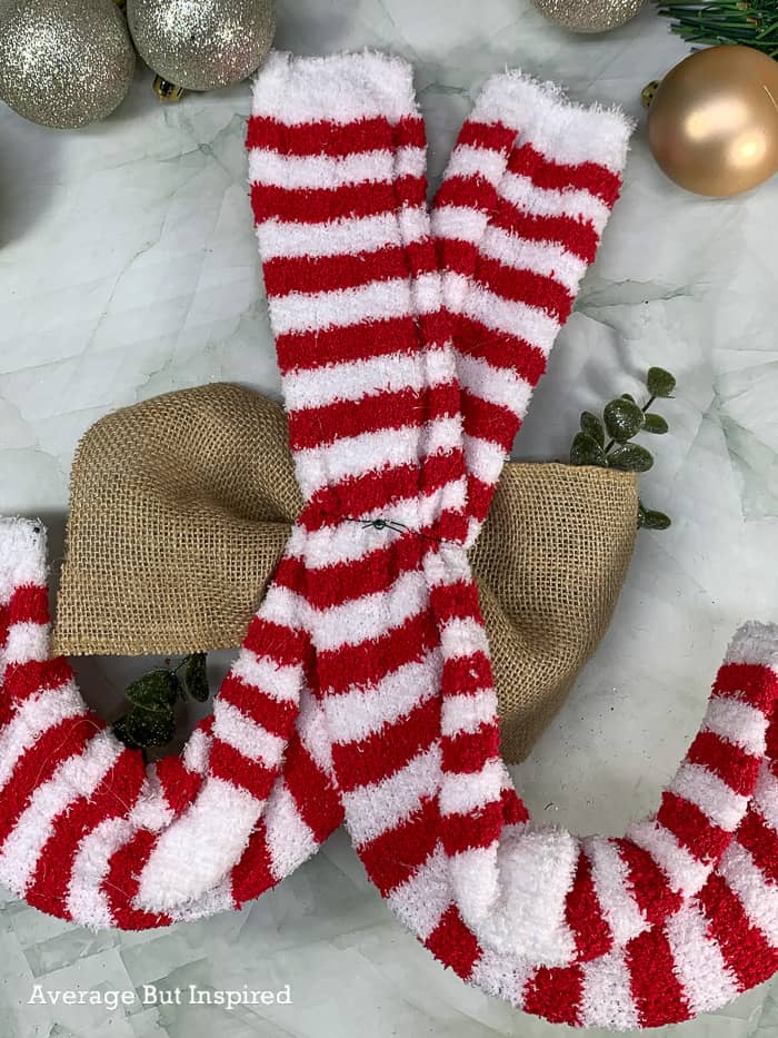 Dollar Tree supplies like the candy cane wreath form and striped socks come together to make an adorable DIY Christmas wreath.