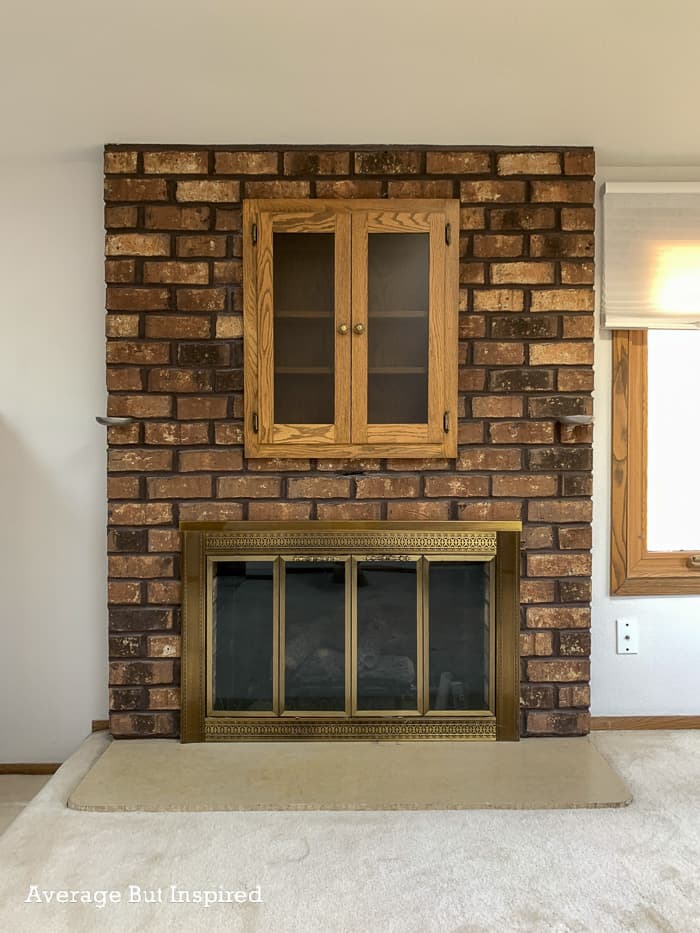This 1970s brick fireplace featured a brass glass door set, a candle holder, built-in match holder, and a shallow depth cabinet. See how the homeowners gave it an updated look with a DIY wood slat treatment.