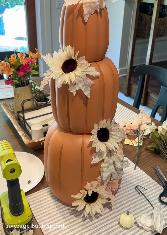 Glue fall leaves and fall flowers to plastic pumpkins to create a pretty pumpkin topiary