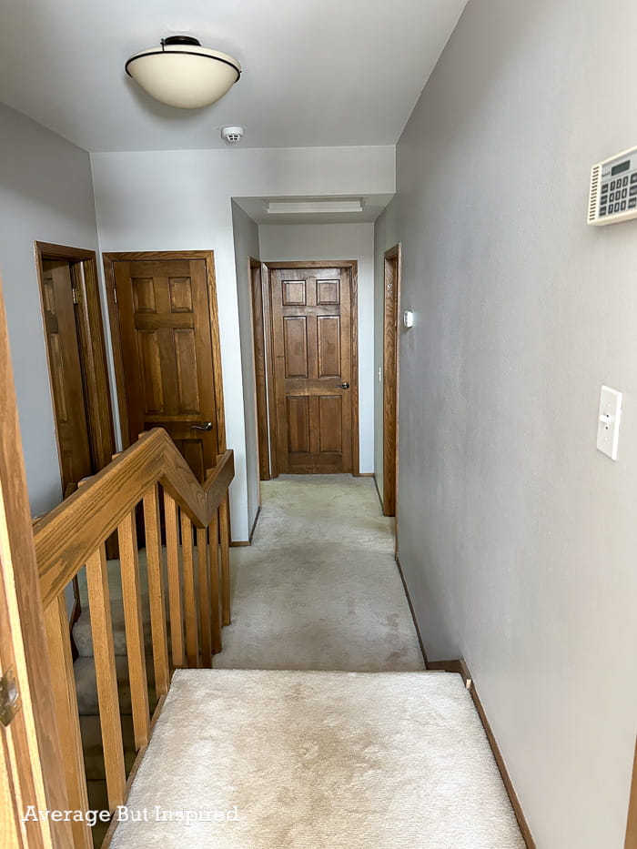 BEFORE: This dark hallway had wood doors and wood trim, gray paint, and an undersized light fixture.