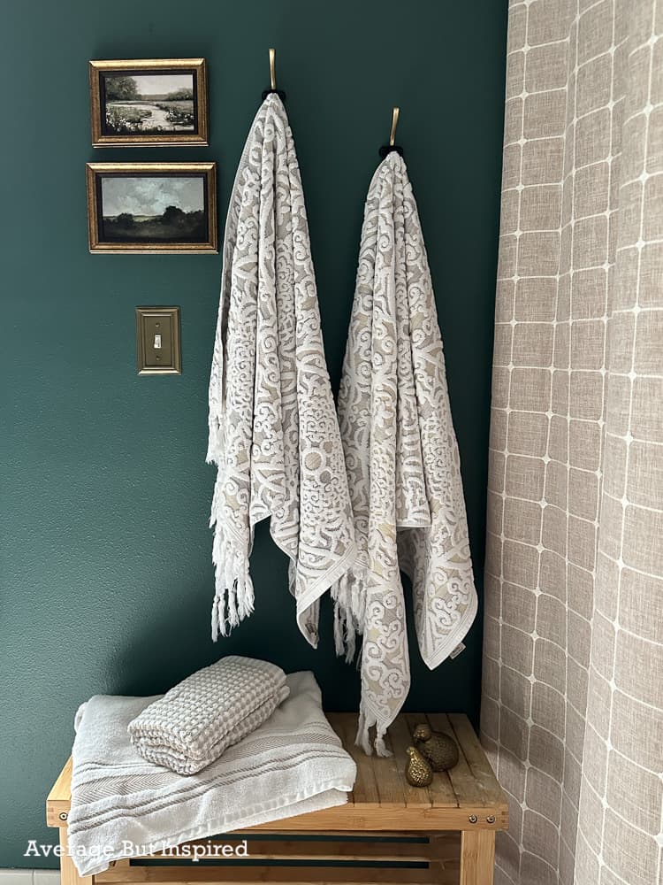 Bathroom painted in BEHR Hidden Gem, the 2026 Color of the Year. Vanity is in BEHR Smoked Tan from the 2026 Color Trends Palette. It features oak wood accents and vintage styling for a moody and cozy bathroom look.