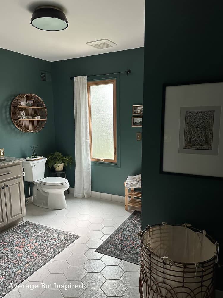 Bathroom painted in BEHR Hidden Gem, the 2026 Color of the Year. Vanity is in BEHR Smoked Tan from the 2026 Color Trends Palette. It features oak wood accents and vintage styling for a moody and cozy bathroom look.